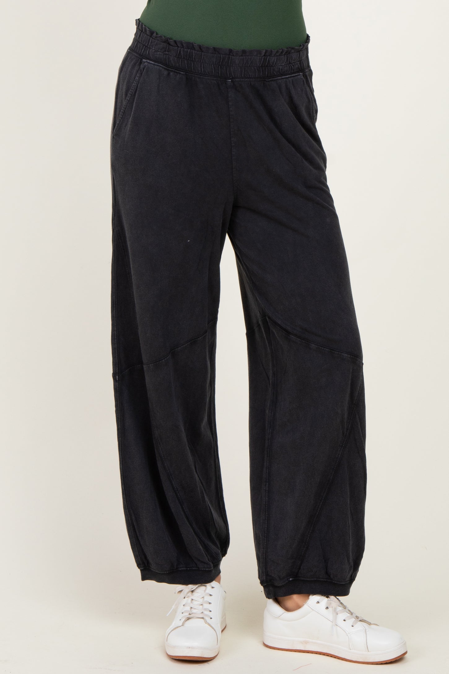 woman wearing black relaxed fit jogger pants with an elastic waistband and side pockets paired with white sneakers