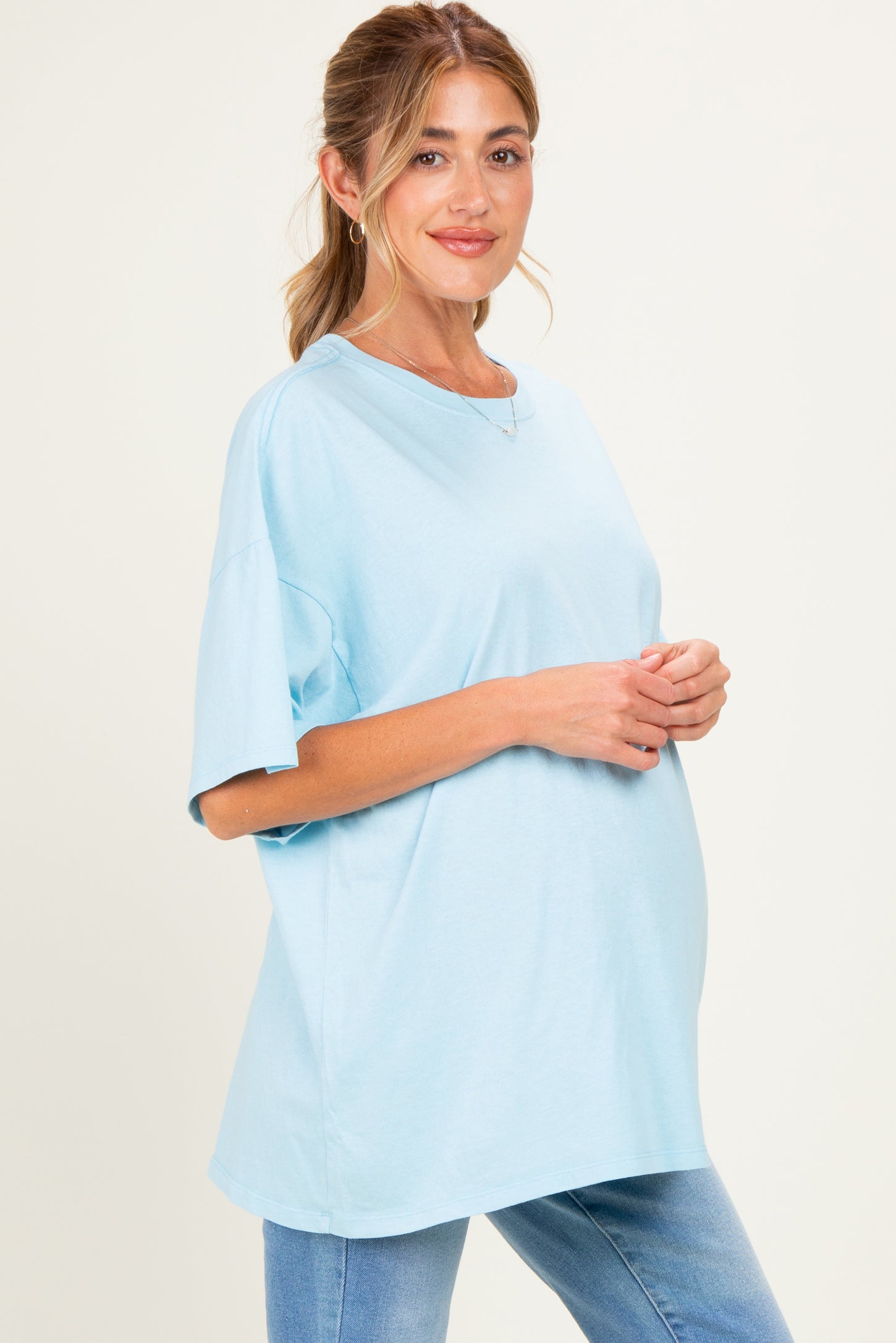 woman wearing a light blue oversized maternity t-shirt with a visible baby bump