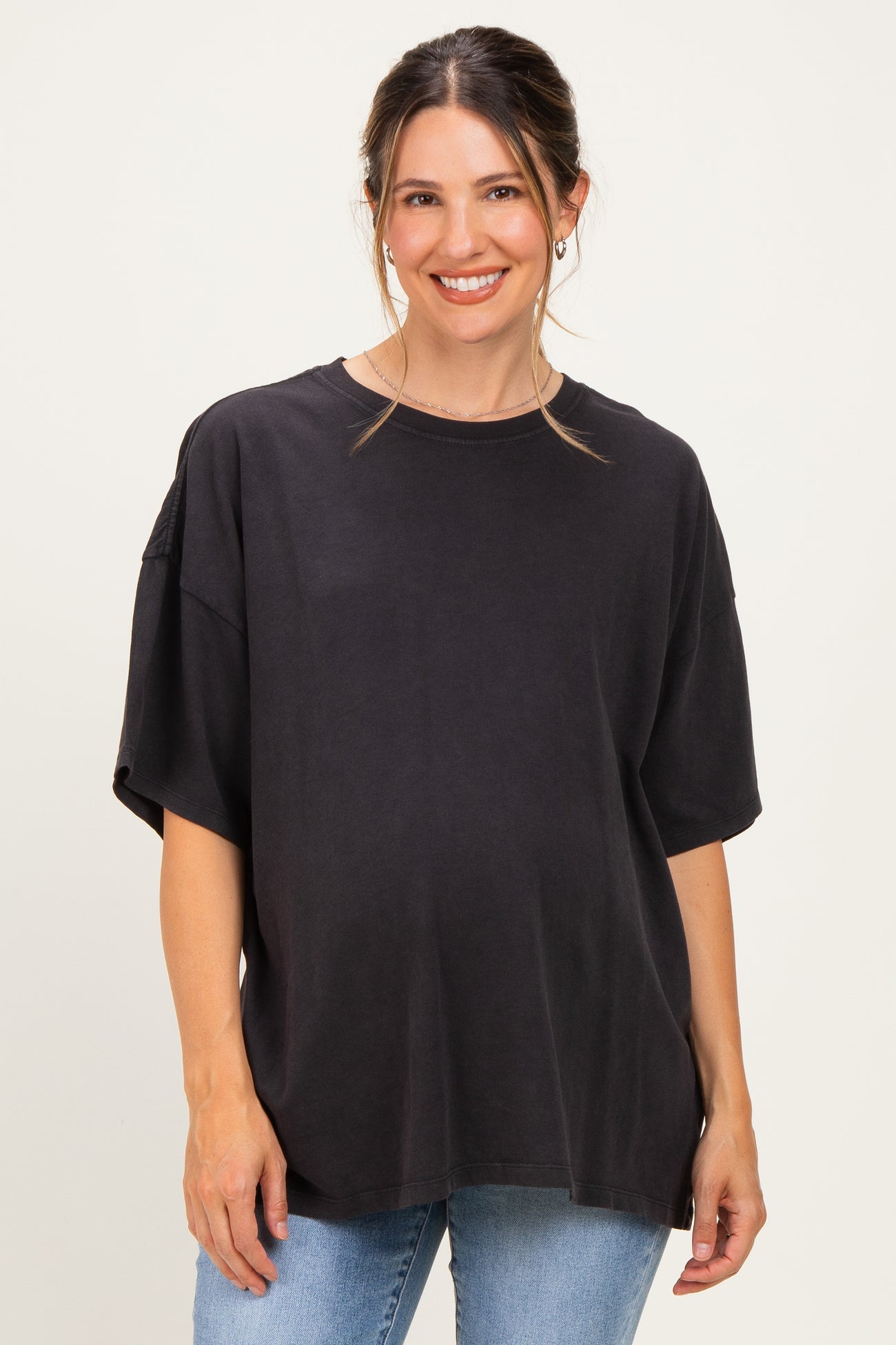 woman wearing a dark gray oversized maternity t-shirt and blue jeans with a visible baby bump