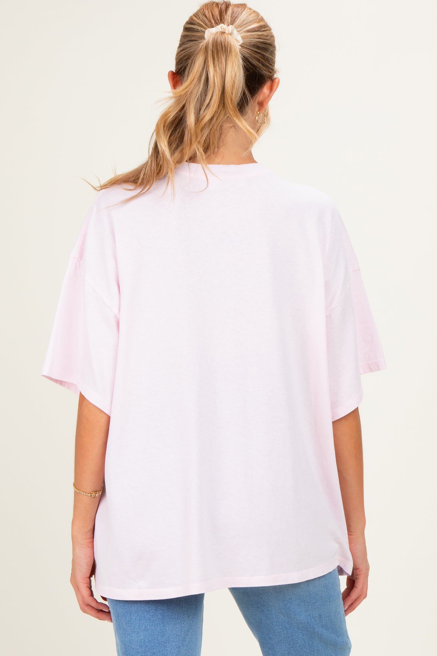 woman wearing a loose-fitting light pink maternity t-shirt with short sleeves and a round neckline