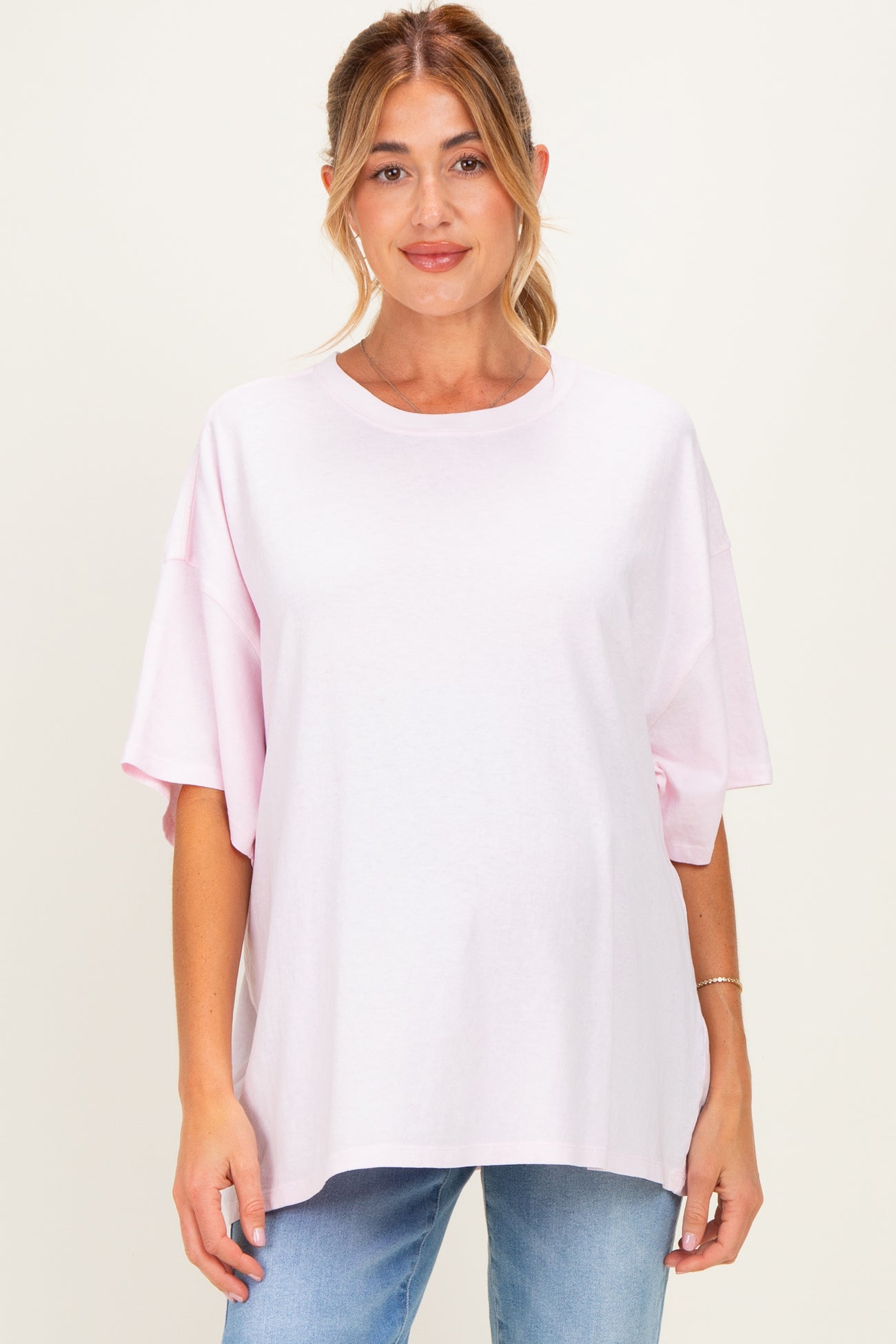 woman wearing a light pink oversized maternity t-shirt with short sleeves and a relaxed fit