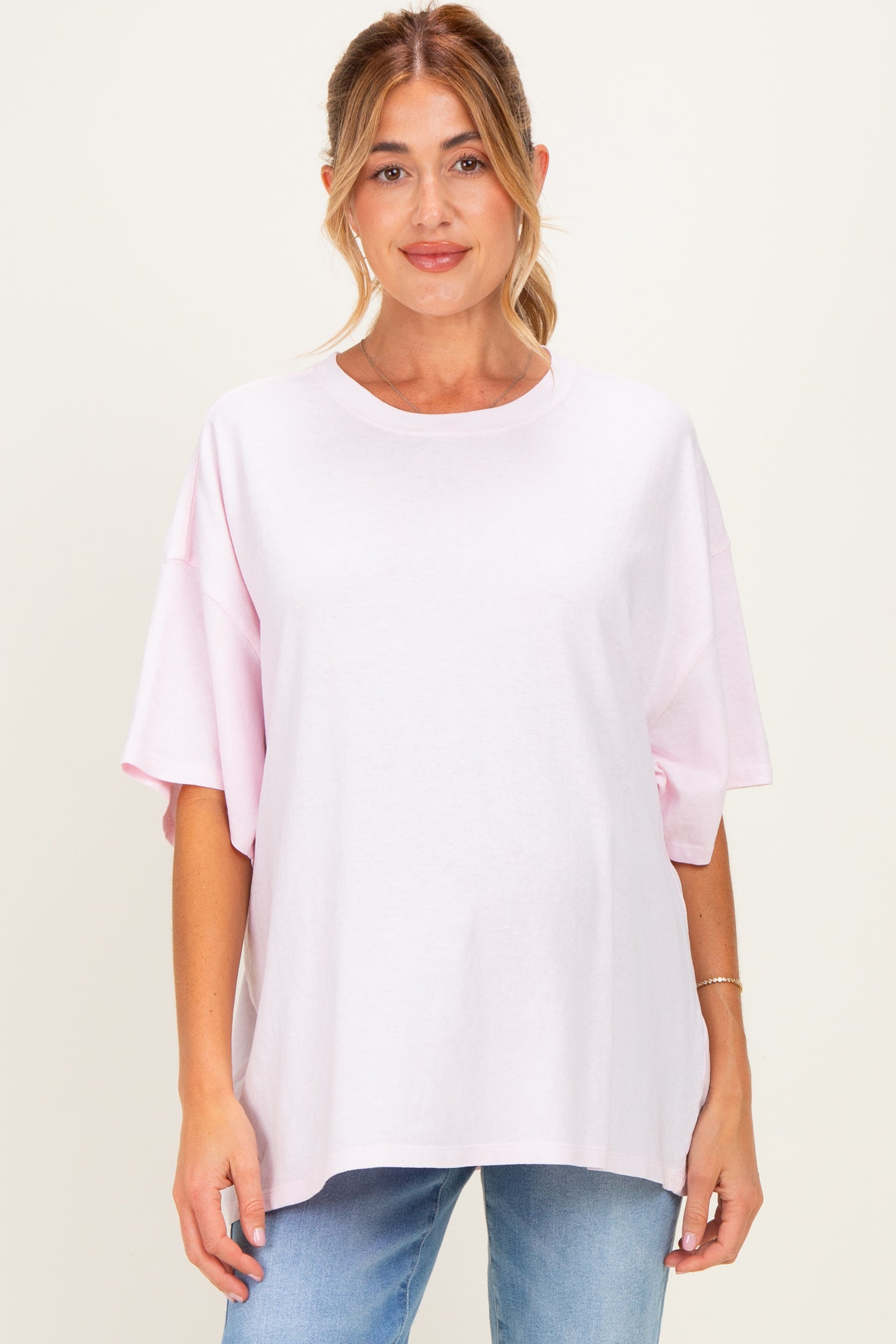 woman wearing a light pink oversized maternity t-shirt with short sleeves and a relaxed fit
