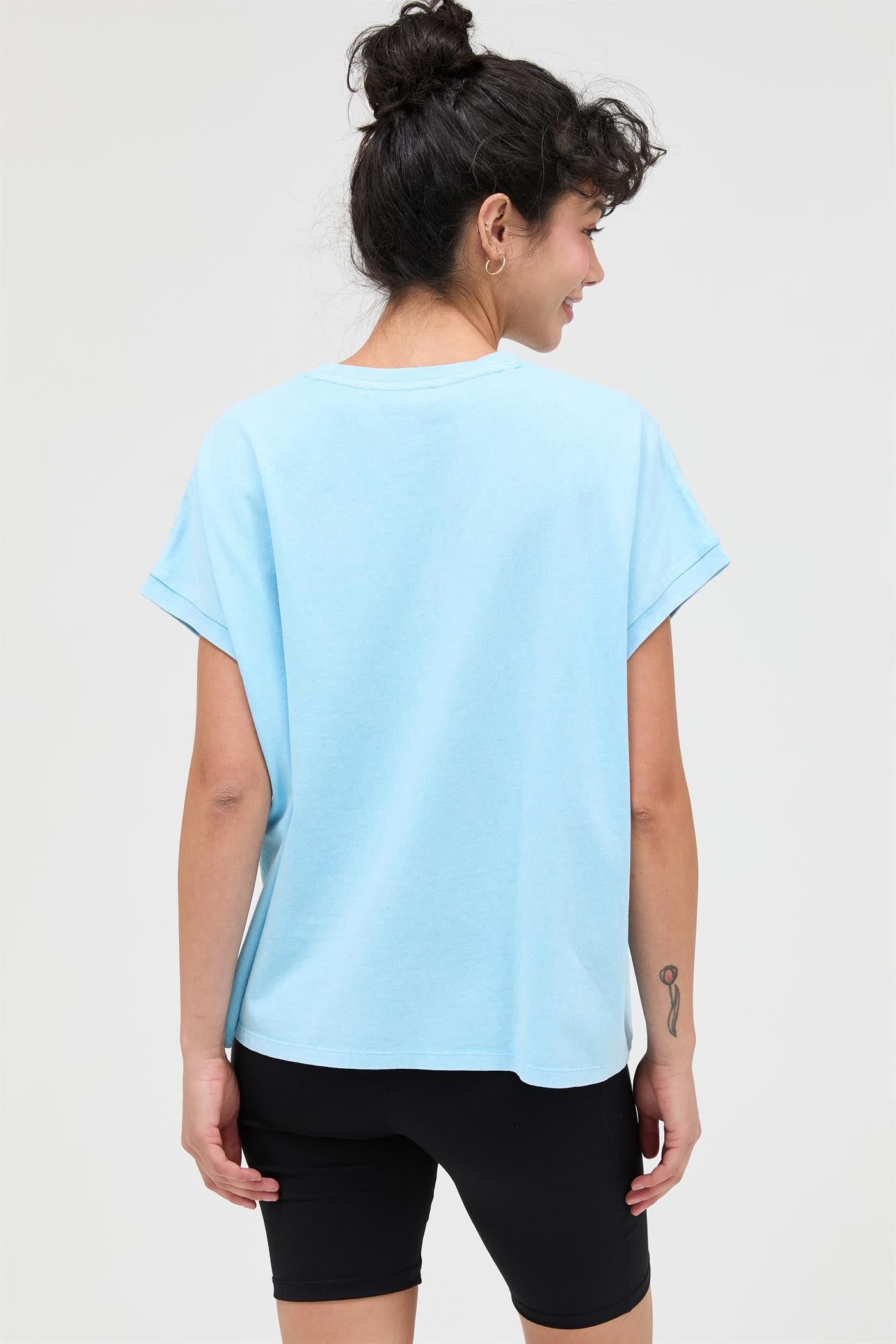 woman wearing a light blue oversized t-shirt and black bike shorts from the back