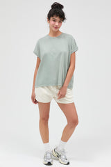 woman wearing a relaxed fit light green t-shirt and casual cream shorts, posing with hands on hips