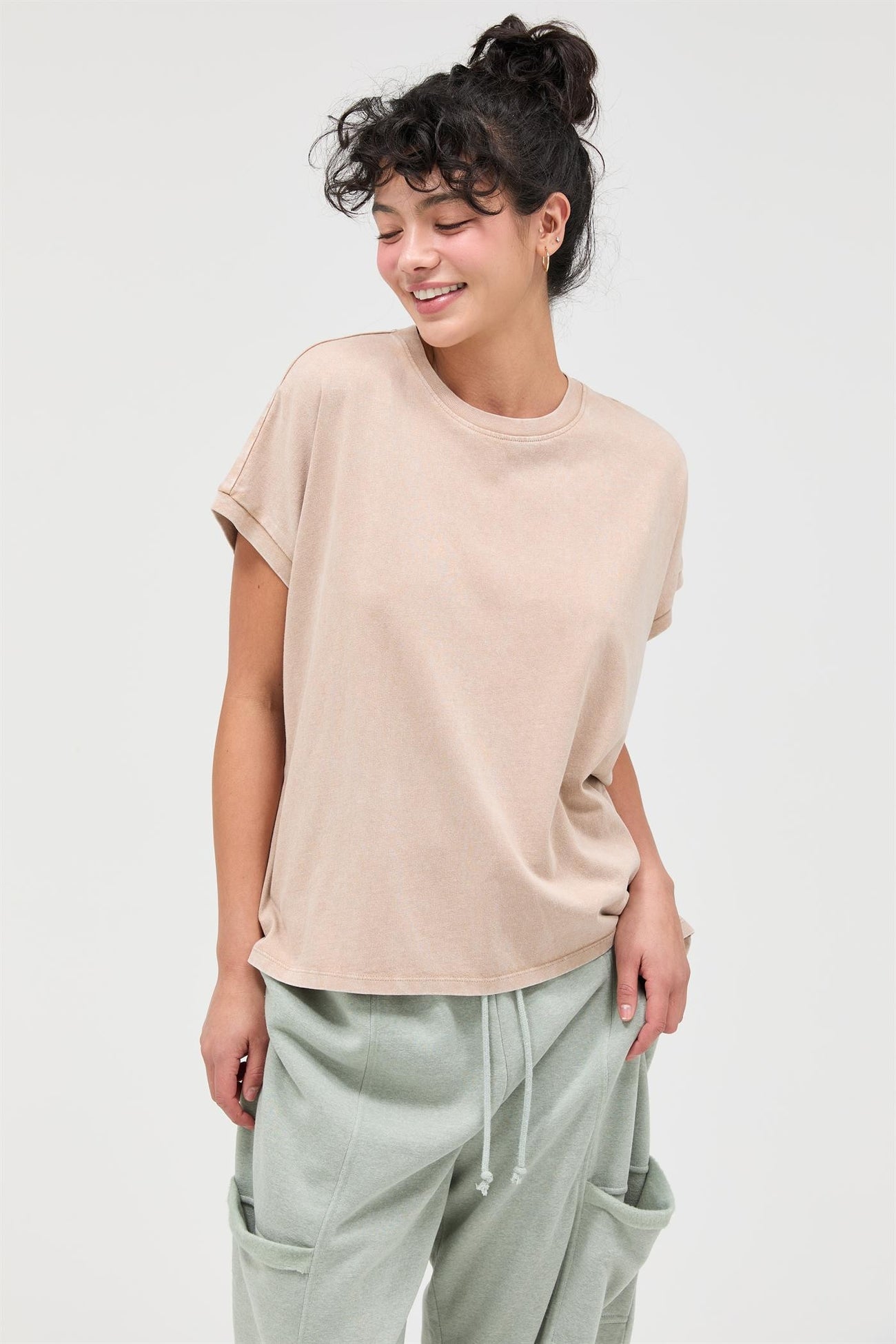 woman wearing a taupe oversized t-shirt with rolled sleeves and light green joggers