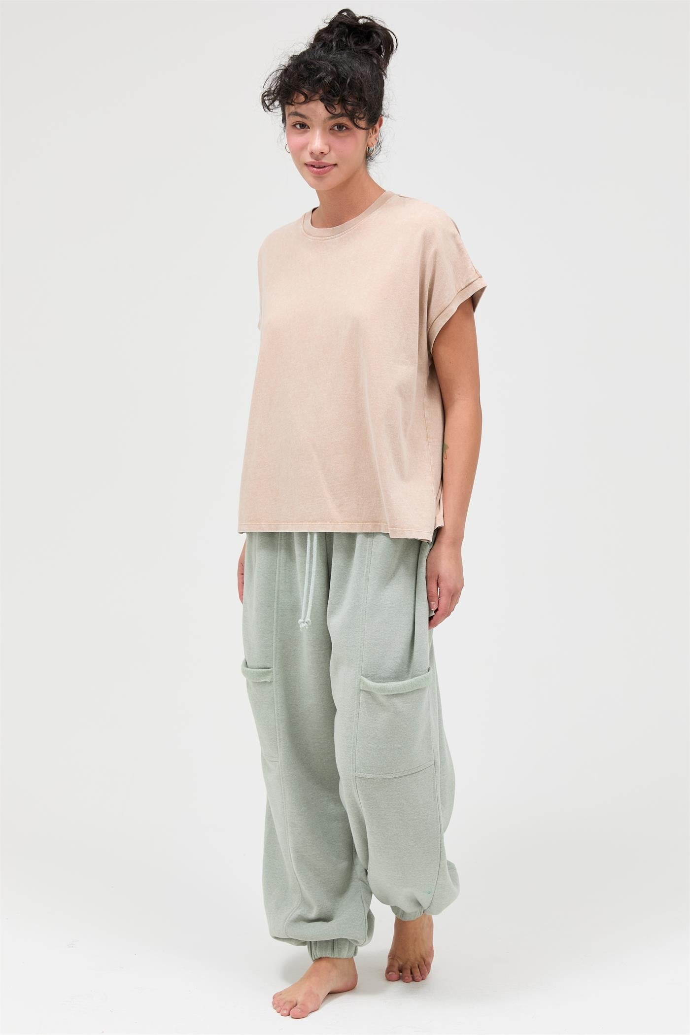 woman wearing a beige oversized t-shirt and light green baggy sweatpants with pockets