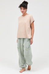 woman wearing a beige oversized t-shirt and light green baggy sweatpants with pockets