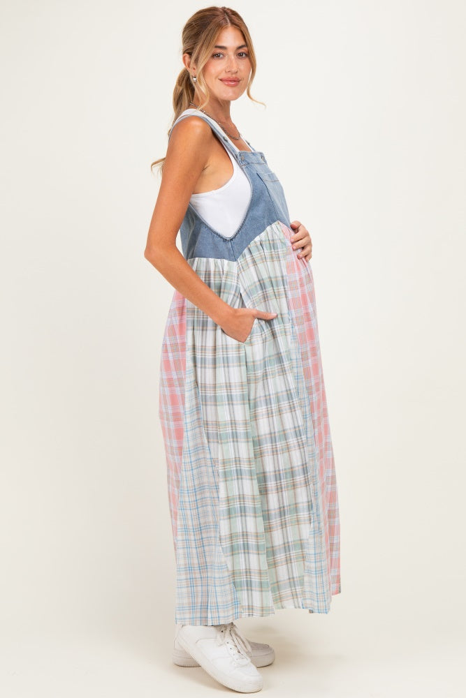 woman wearing a denim and plaid maternity maxi dress with a baby bump, featuring adjustable straps and pockets