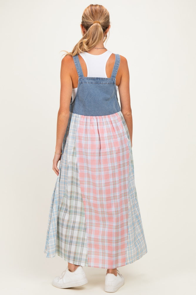 woman wearing a denim and plaid color block maternity dress with adjustable straps and a flowy skirt