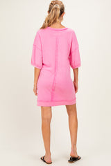 woman wearing a pink oversized maternity dress with short sleeves, showing the back view