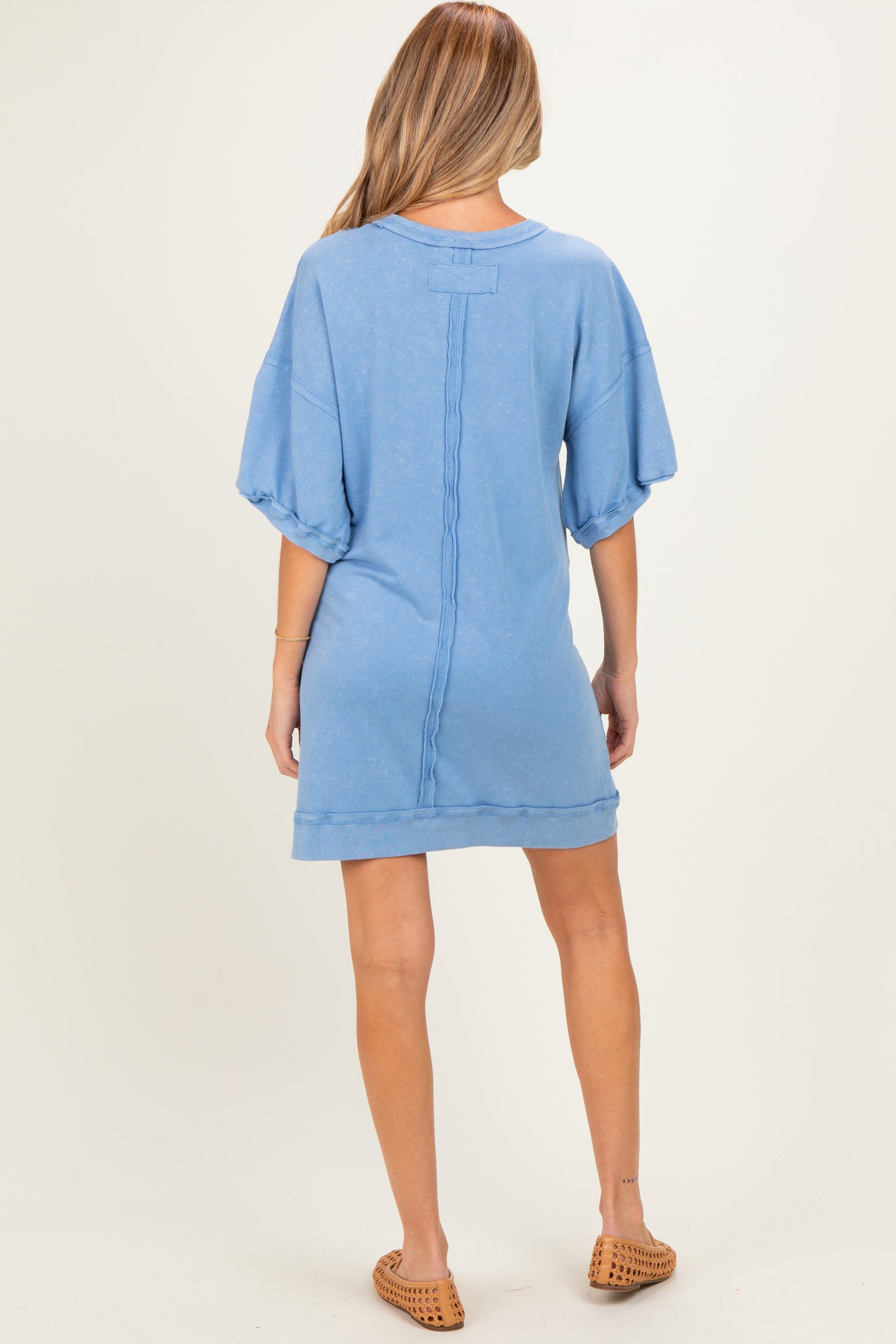 woman wearing a relaxed fit light blue maternity dress with short sleeves and a distressed hem