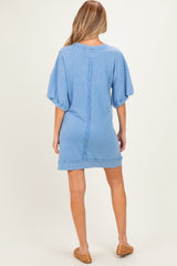 woman wearing a relaxed fit light blue maternity dress with short sleeves and a distressed hem