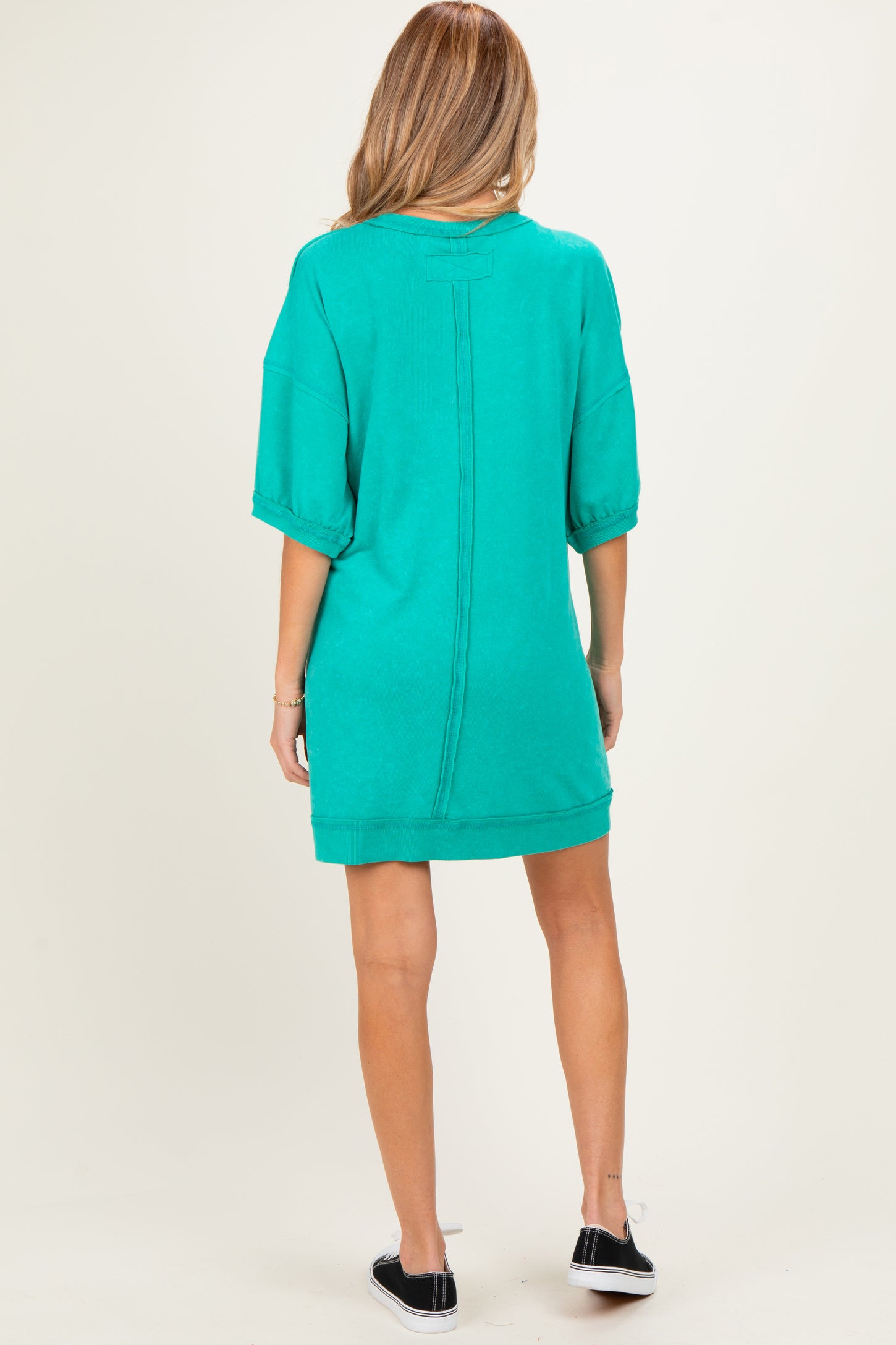 woman wearing a green maternity sweatshirt dress with short sleeves and a relaxed fit, showing the back view