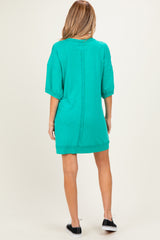 woman wearing a green maternity sweatshirt dress with short sleeves and a relaxed fit, showing the back view