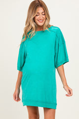 woman wearing a teal oversized maternity dress with short sleeves and a visible baby bump
