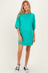 woman wearing a teal maternity oversized t-shirt dress with short sleeves and a visible baby bump