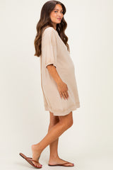 woman wearing a beige oversized maternity dress with short sleeves and a visible baby bump