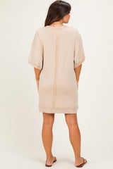 woman wearing a light beige maternity sweatshirt dress with short sleeves and a relaxed fit