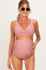 woman wearing a blush pink maternity bikini set with a wrap top and high-waisted bottoms, showing her baby bump