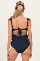 woman wearing a navy blue ribbed maternity swimsuit with ruffled straps and an open back design