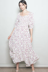 woman wearing a white floral maxi dress with smocked bodice and puff sleeves, standing against a plain background