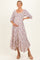 woman wearing a floral maternity midi dress with puff sleeves and a visible baby bump while smiling