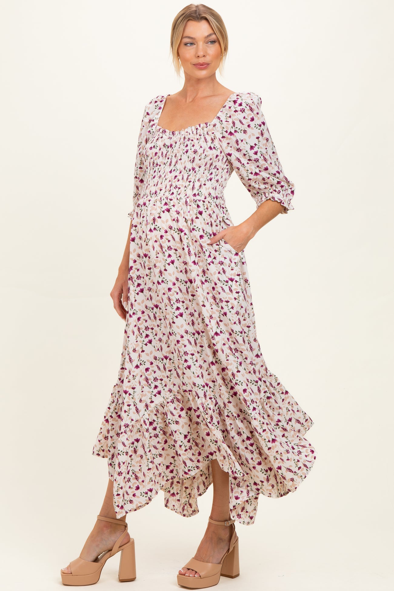 woman wearing a floral maternity dress with a square neckline, smocked bodice, and ruffled hem, showcasing a baby bump