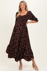 woman wearing a burgundy floral maternity dress with puff sleeves and a tiered skirt, showing her baby bump