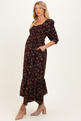 woman wearing a burgundy floral maternity dress with puff sleeves and a ruffled hem, showing her baby bump and pockets