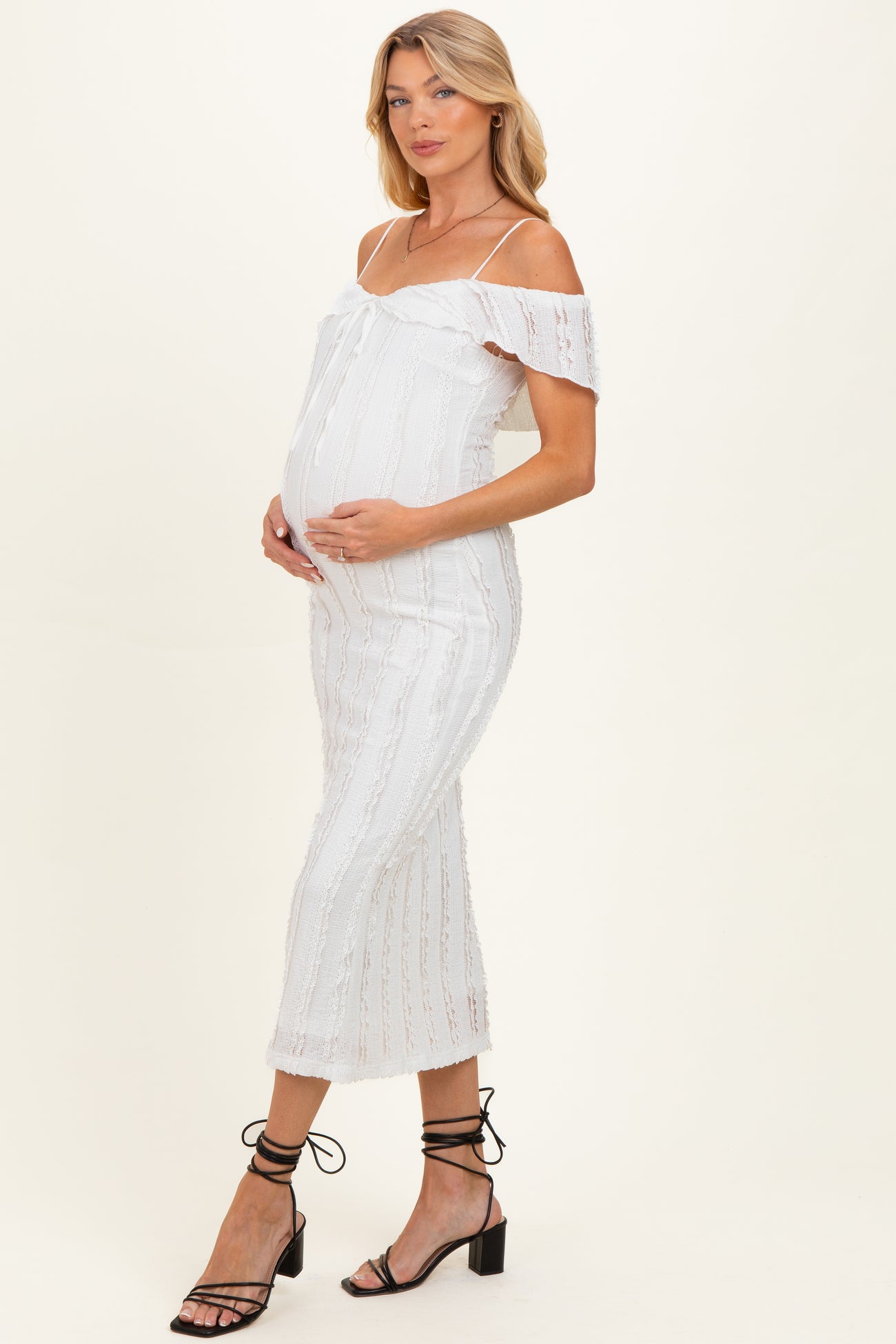 woman wearing a white off-the-shoulder maternity dress with a fitted silhouette and a visible baby bump