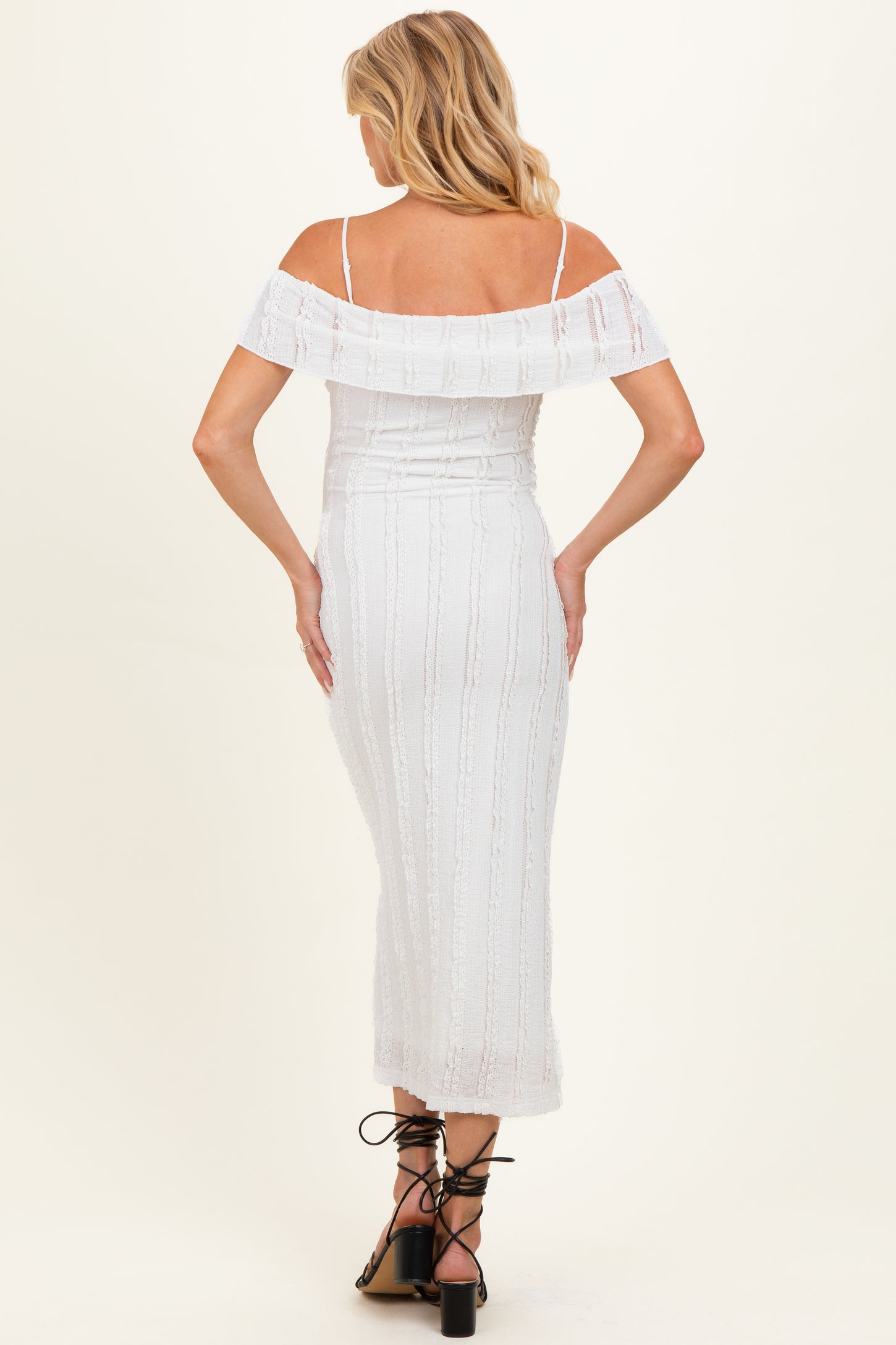 woman wearing a white off-the-shoulder maternity dress with textured detailing and a fitted silhouette