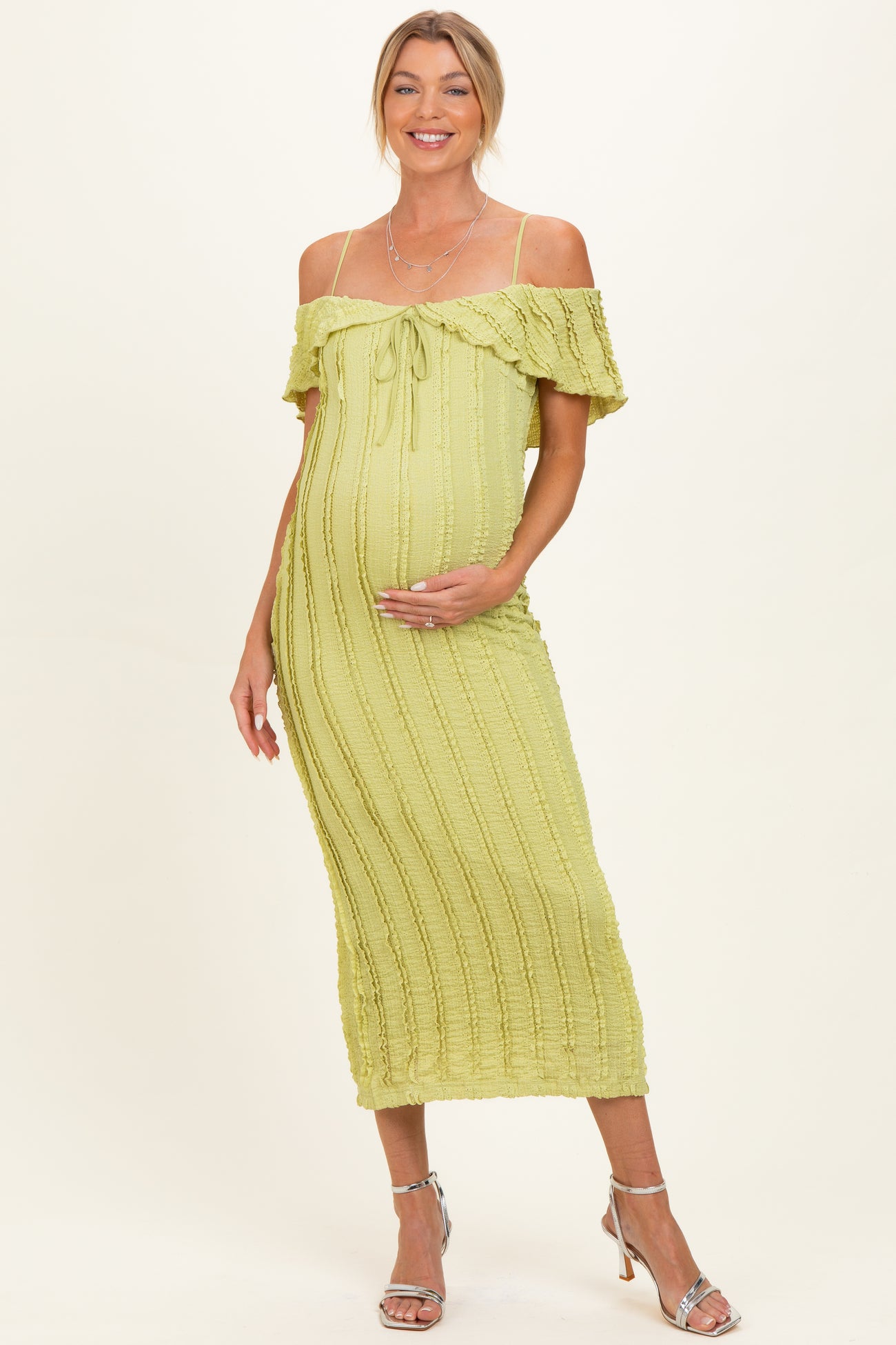 woman wearing a light green off-the-shoulder maternity dress with a fitted silhouette and a baby bump