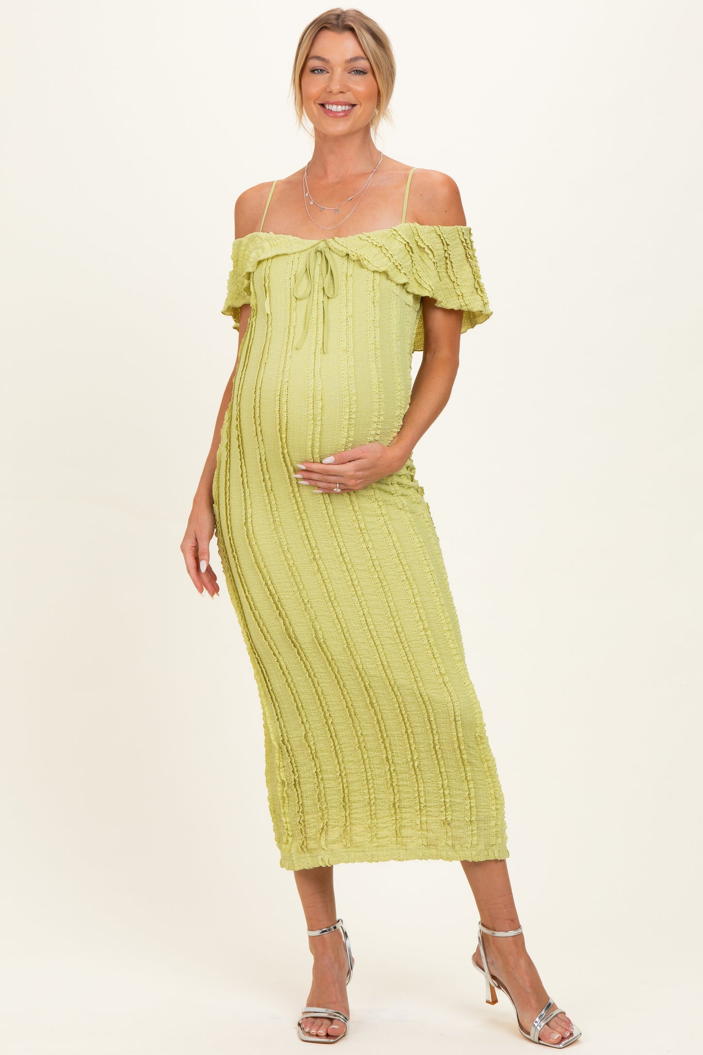 woman wearing a light green off-the-shoulder maternity dress with a fitted silhouette and a baby bump