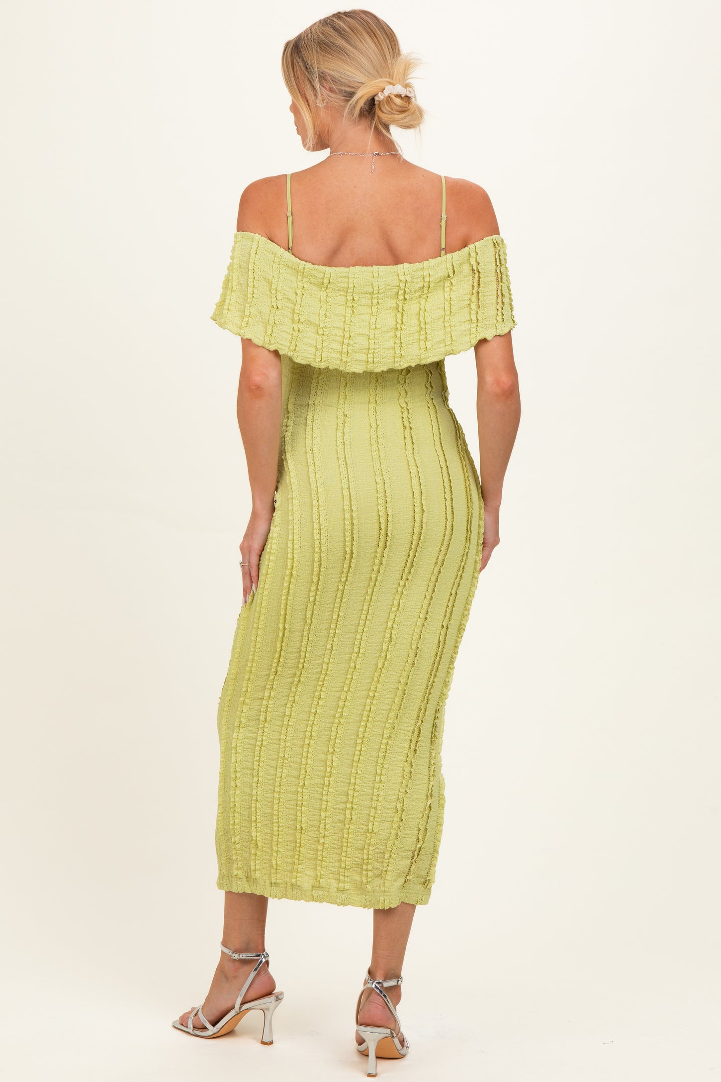 woman wearing a light green off-the-shoulder maternity dress with a textured design and a fitted silhouette