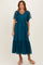 woman wearing a teal midi dress with dotted sheer puff sleeves and a tiered tulle skirt, standing in beige block-heeled sandals