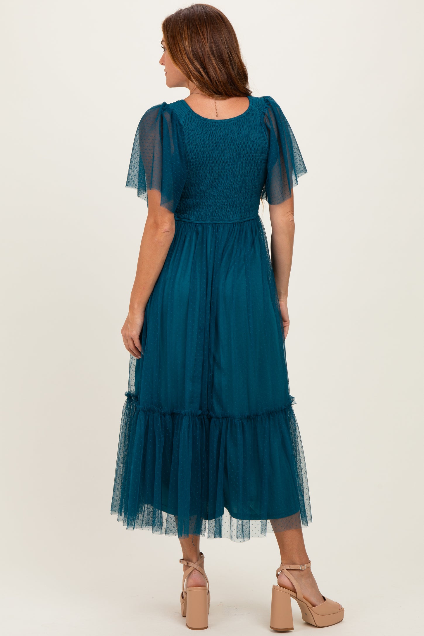 woman wearing a teal maxi dress with short tulle sleeves and a tiered skirt, seen from the back
