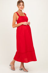 woman wearing a red maternity maxi dress with a square neckline and adjustable straps, showcasing her baby bump