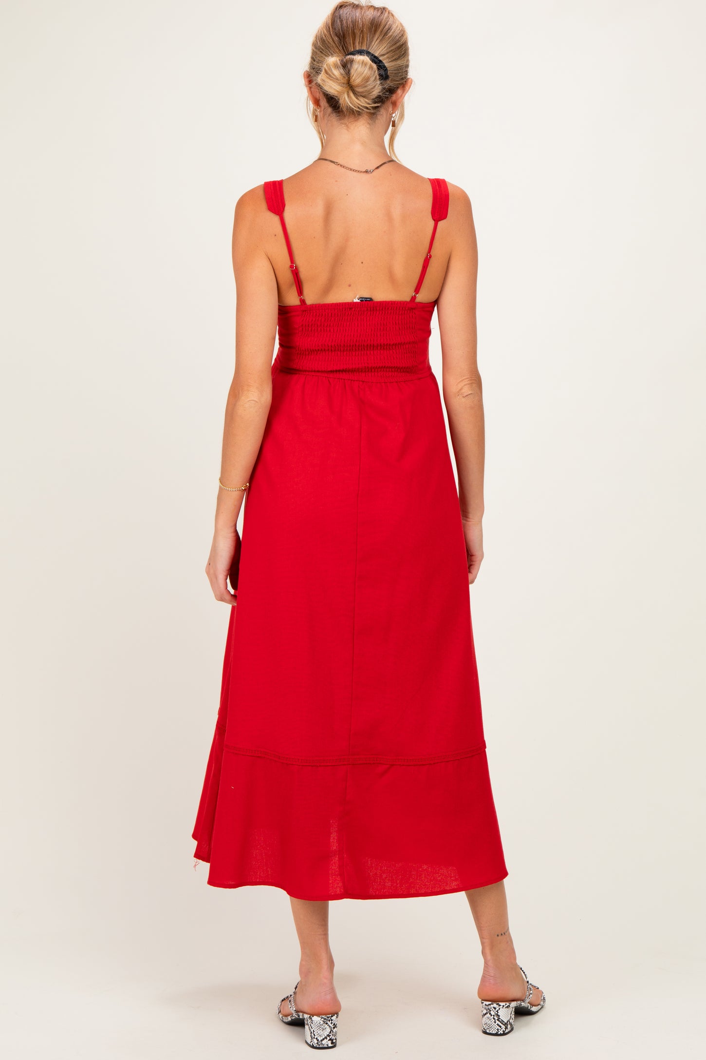 woman wearing a red maternity maxi dress with smocked bodice and adjustable straps, showing a baby bump