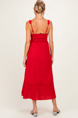woman wearing a red maternity maxi dress with smocked bodice and adjustable straps, showing a baby bump