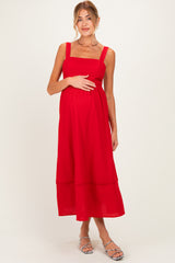 woman wearing a red maternity dress with square neckline and tiered hem, holding her baby bump