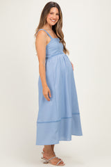 woman wearing a light blue maternity maxi dress with a fitted bodice and flowy skirt, highlighting her baby bump