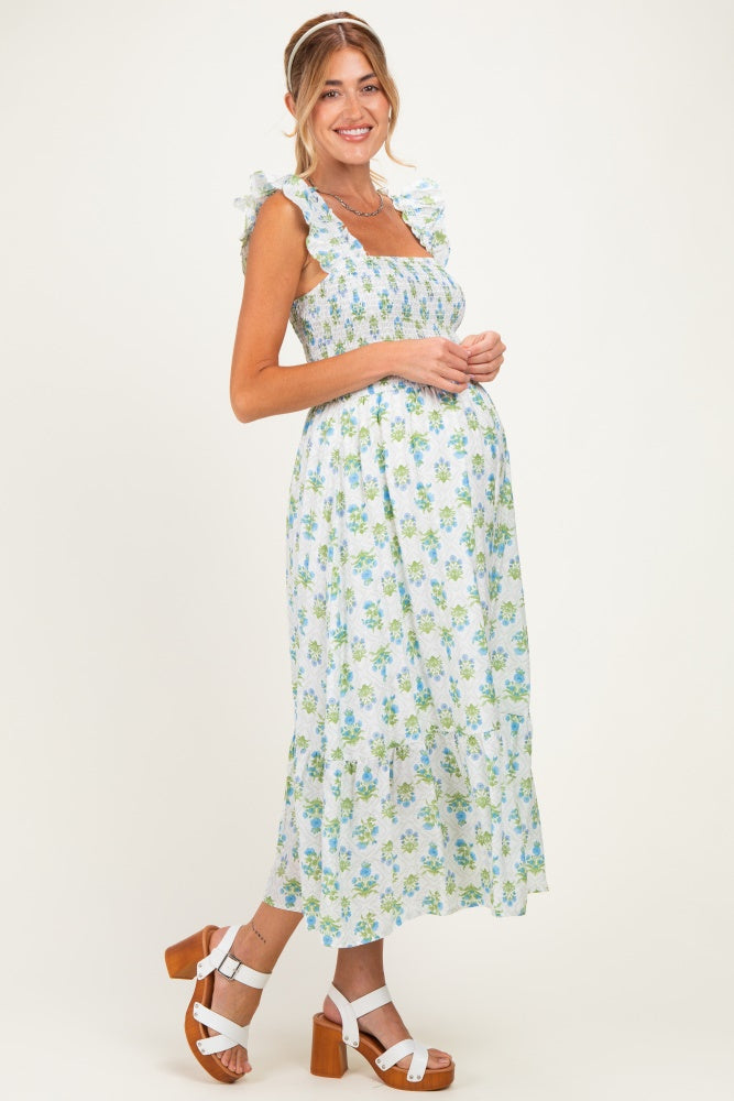woman wearing a light blue floral maternity dress with ruffled straps and a flowing skirt, showcasing her baby bump