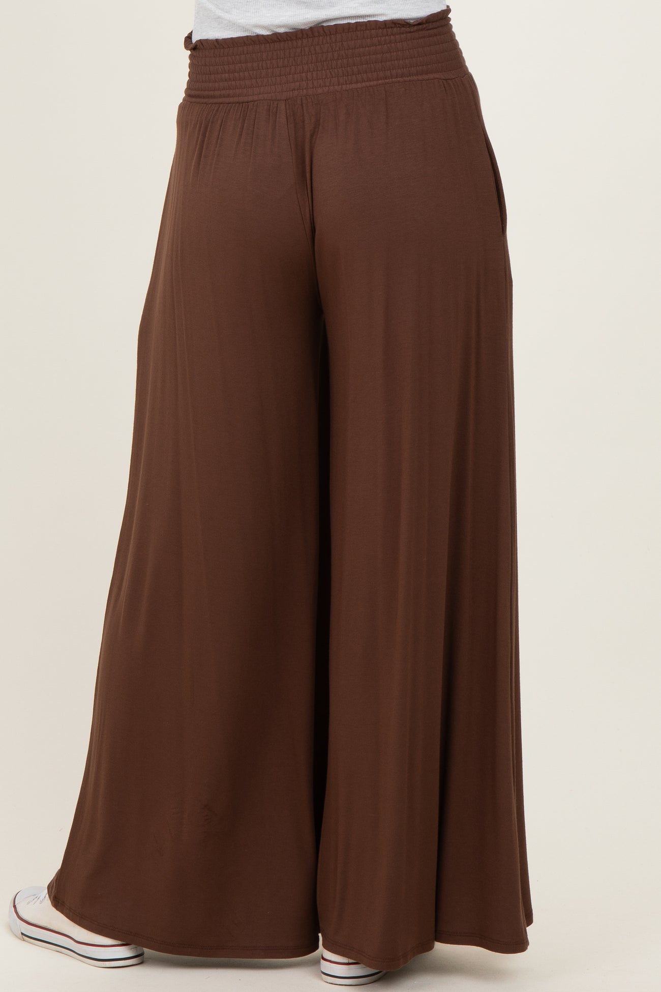 woman wearing brown wide-leg pants with a smocked waistband and a relaxed fit, viewed from the back