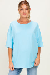 woman wearing a light blue oversized maternity top with short sleeves and a relaxed fit