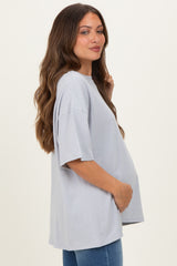 woman wearing a light gray oversized maternity t-shirt and holding her baby bump