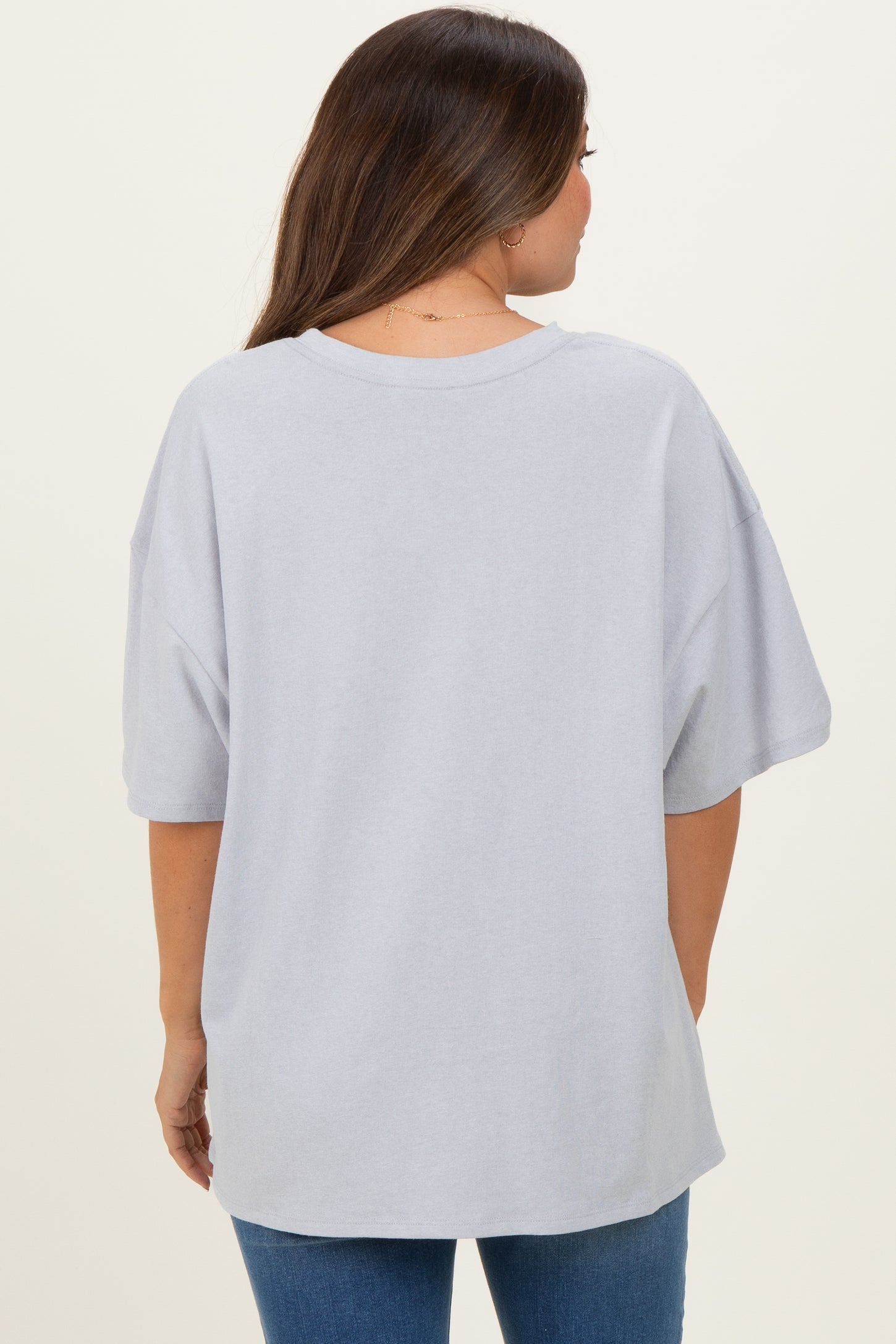 woman wearing a grey oversized maternity t-shirt, viewed from the back, paired with blue jeans