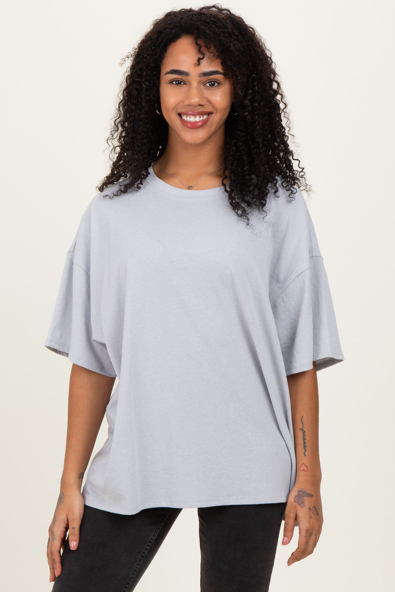 woman wearing an oversized light gray t-shirt with short sleeves and a relaxed fit