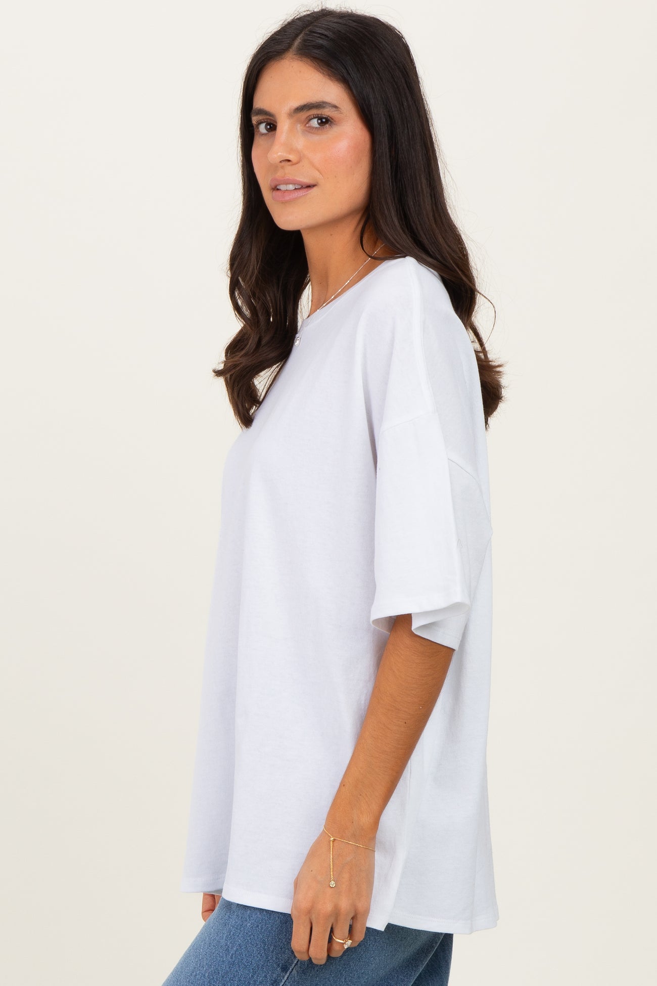 woman wearing a loose-fitting white t-shirt with short sleeves and a relaxed silhouette, styled with blue jeans