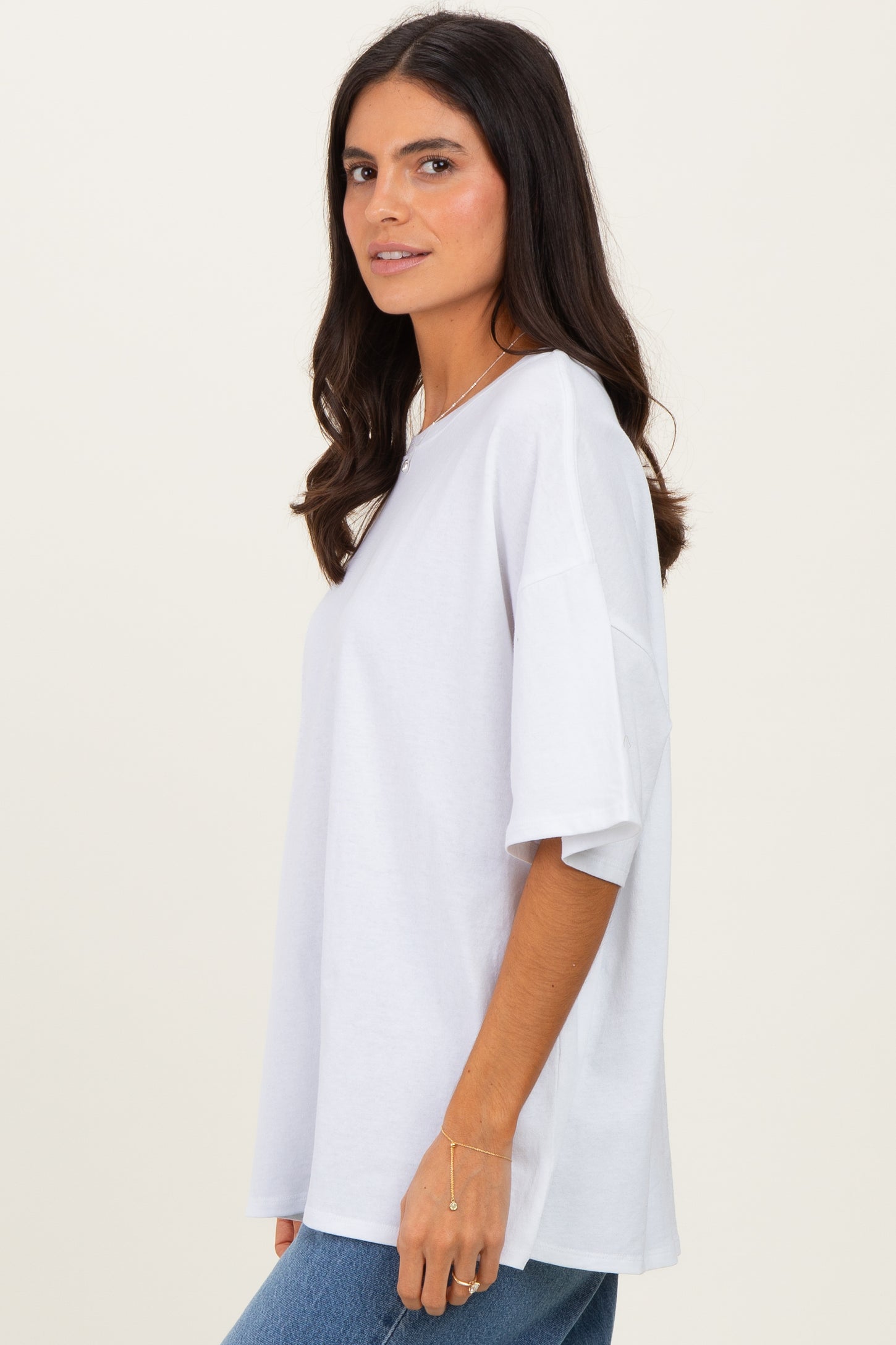 woman wearing a loose-fitting white t-shirt with short sleeves and a relaxed silhouette, styled with blue jeans