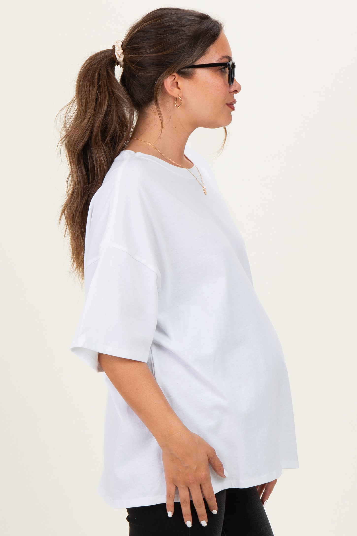 woman wearing a white oversized maternity t-shirt with a visible baby bump and sunglasses